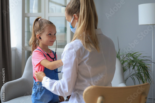 Little girl at the doctor for a checkup. Child auscultate the heartbeat of the doctor. photo