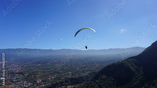 Paraglider flying above the North coast of Tenerife, Canary Islands, Spain; sky and mountains background