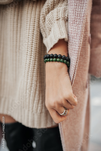 Tibetan talisman bracelet with minerals and magic dzi bead on woman hand in pink powdery delicate knitted jacket. energy trappings. autumn still life bracelet in leaves on wood. selective focus