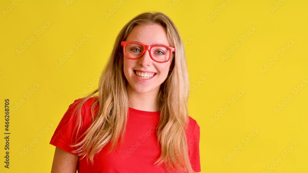 Beautiful young woman in red t shirt smiles over vibrant yellow background Beautiful young woman in red t shirt smiles over vibrant yellow background