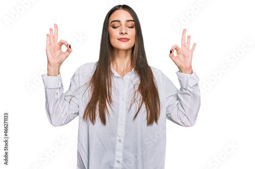 Young beautiful woman wearing casual white shirt relax and smiling with eyes closed doing meditation gesture with fingers. yoga concept.