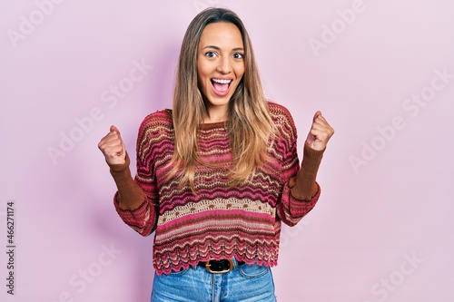 Beautiful hispanic woman wearing hippie sweater celebrating surprised and amazed for success with arms raised and open eyes. winner concept. © Krakenimages.com