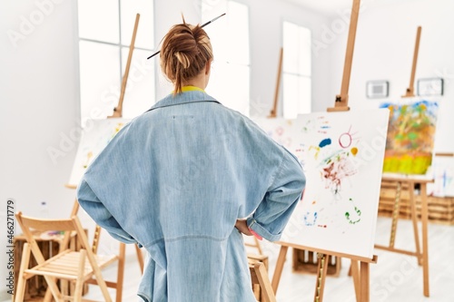 Young caucasian girl at art studio standing backwards looking away with arms on body