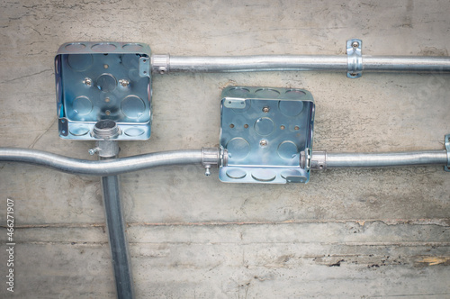 Electrical conduit for cable routing between electrical distribution panel with Galvanized electrical junction box and Pipe of electricity line installed in buildings. Selective focus.