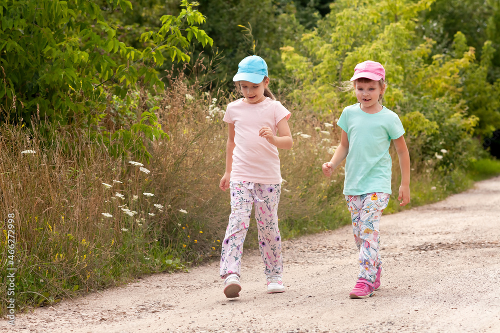Two elementary school age girls wandering, children, sisters walking together through a country road, rural area. Taking a walk, kids strolling, togetherness and outdoors exploration concept, nature Two elementary school age girls wandering, children, sisters walking together through a country road, rural area. Taking a walk, kids strolling, togetherness and outdoors exploration concept, nature