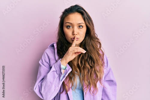 Young hispanic girl wearing casual clothes asking to be quiet with finger on lips. silence and secret concept.