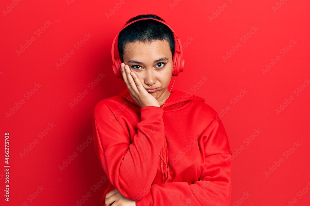 Fototapeta premium Beautiful hispanic woman with short hair listening to music using headphones thinking looking tired and bored with depression problems with crossed arms.