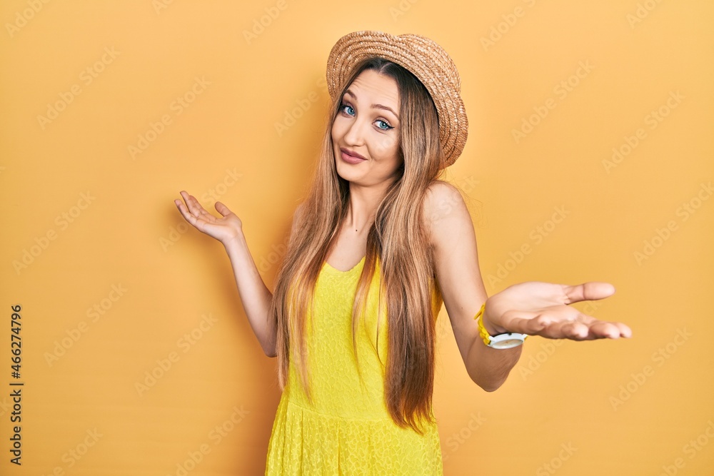Young blonde girl wearing summer hat clueless and confused expression with arms and hands raised. doubt concept. Young blonde girl wearing summer hat clueless and confused expression with arms and hands raised. doubt concept.