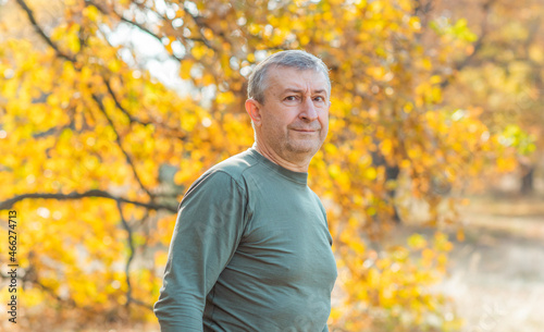 Mature European man with a good mood, outdoor portrait at autumn park . The concept of life after 50 years 