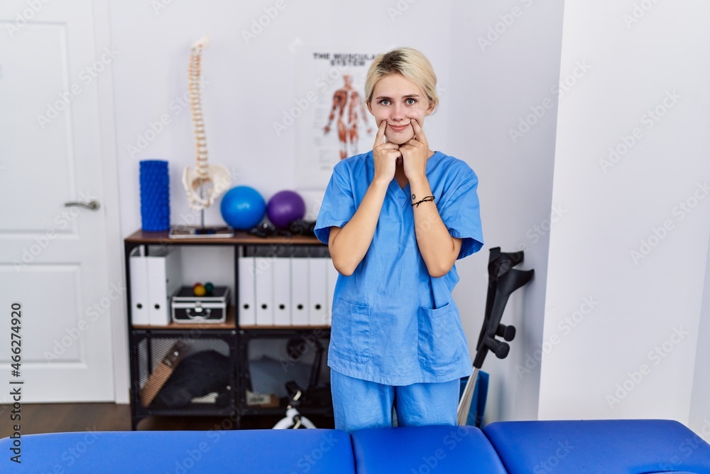 Young physiotherapist woman working at pain recovery clinic smiling with open mouth, fingers pointing and forcing cheerful smile Young physiotherapist woman working at pain recovery clinic smiling with open mouth, fingers pointing and forcing cheerful smile