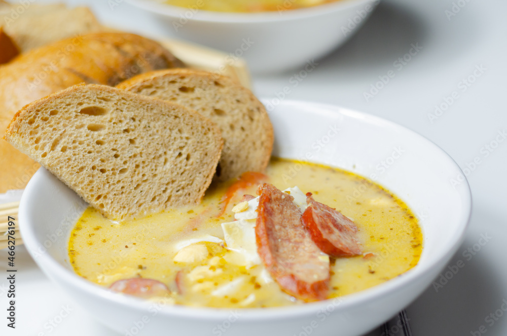 Traditional polish sour soup with sausage and eggs in ceramic bowl Traditional polish sour soup with sausage and eggs in ceramic bowl