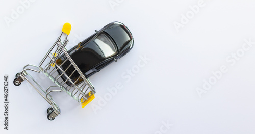 Mini car in mini shopping cart isolated on white background. Buying auto. Personal vehicle. Top view, flat lay with space for text.