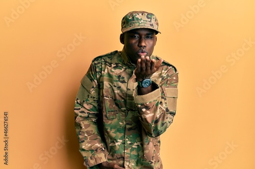 Obraz na plátně Young african american man wearing army uniform looking at the camera blowing a kiss with hand on air being lovely and sexy