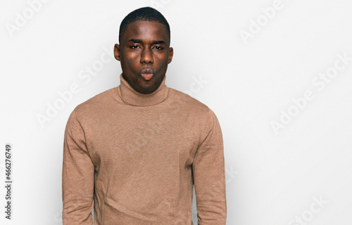 Young african american man wearing casual winter sweater making fish face with lips, crazy and comical gesture. funny expression.