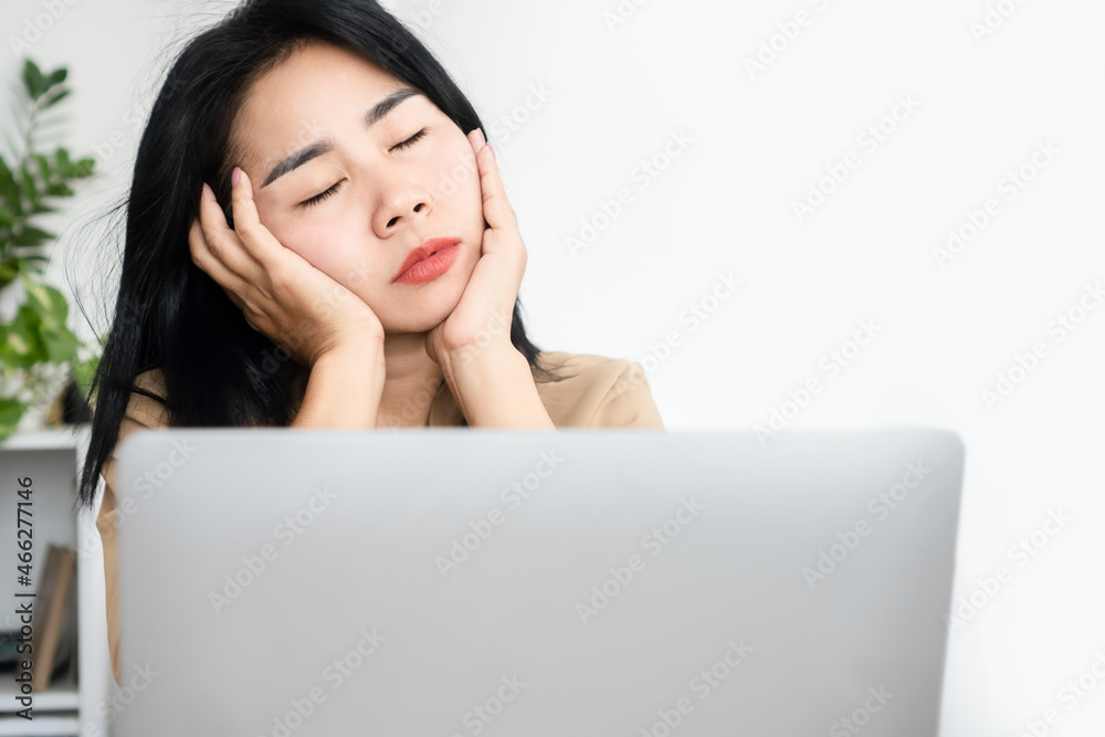 sleepy Asian businesswoman fall asleep at office desk while working on laptop sleepy Asian businesswoman fall asleep at office desk while working on laptop