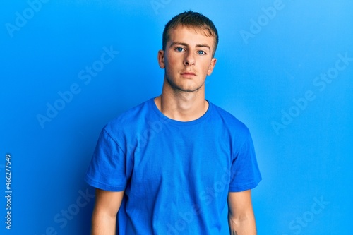 Young caucasian man wearing casual blue t shirt relaxed with serious expression on face. simple and natural looking at the camera.