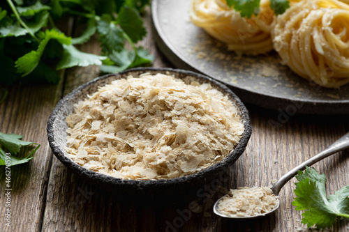 Canvas Print Nutritional yeast flakes on wooden background , selective focus