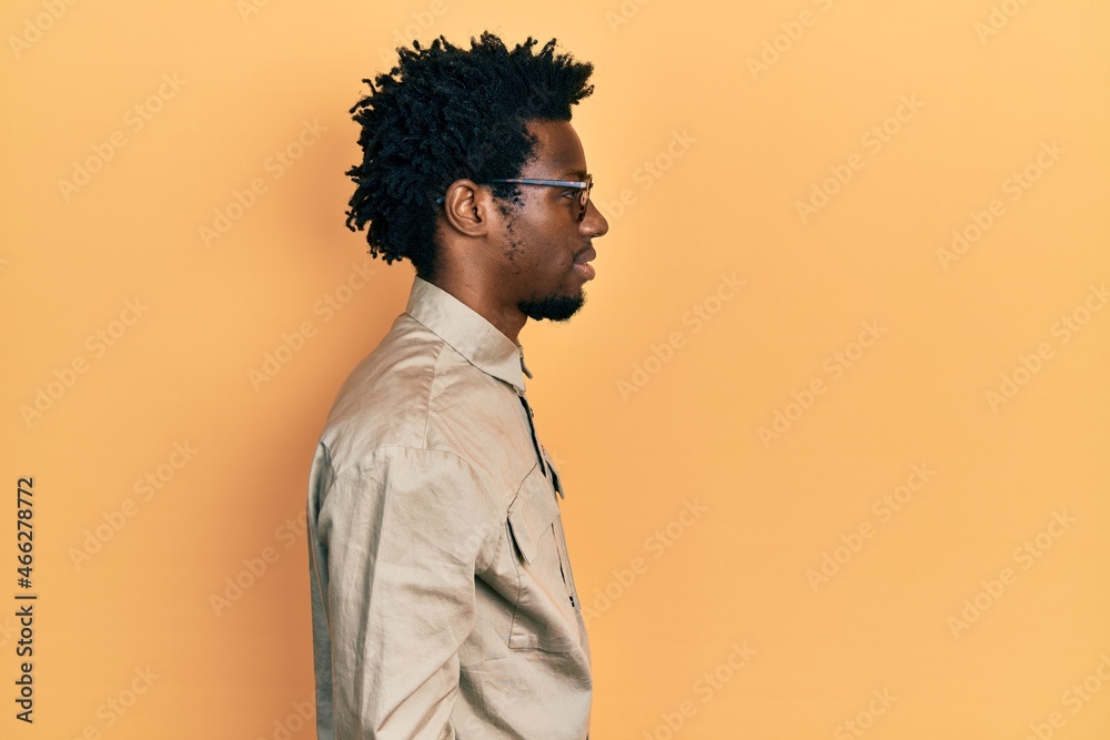 Young african american man wearing casual clothes and glasses looking to side, relax profile pose with natural face with confident smile. Young african american man wearing casual clothes and glasses looking to side, relax profile pose with natural face with confident smile.