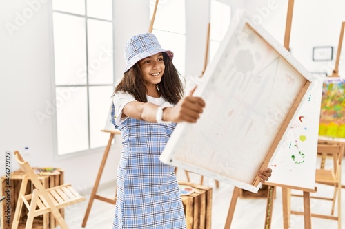 African american girl smiling confident holding canvas at art school