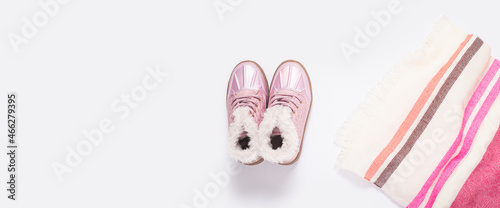 Boots for a child girl and a striped scarf on a white background. Top view, flat lay. Banner.