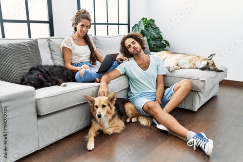 Young hispanic couple with dogs relaxing at home looking sleepy and tired, exhausted for fatigue and hangover, lazy eyes in the morning. © Krakenimages.com