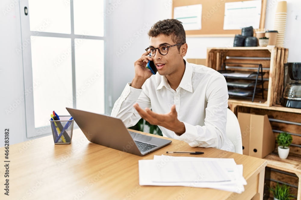 Young hispanic man working speaking on the phone at business office Young hispanic man working speaking on the phone at business office