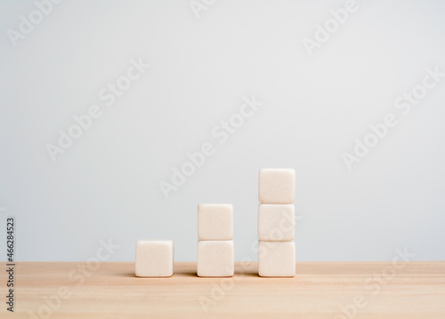 Growth and success business chart built with white blocks as steps on wood table, white background with copy space. Increase revenue, benefit, profit, and economic improvement concept.