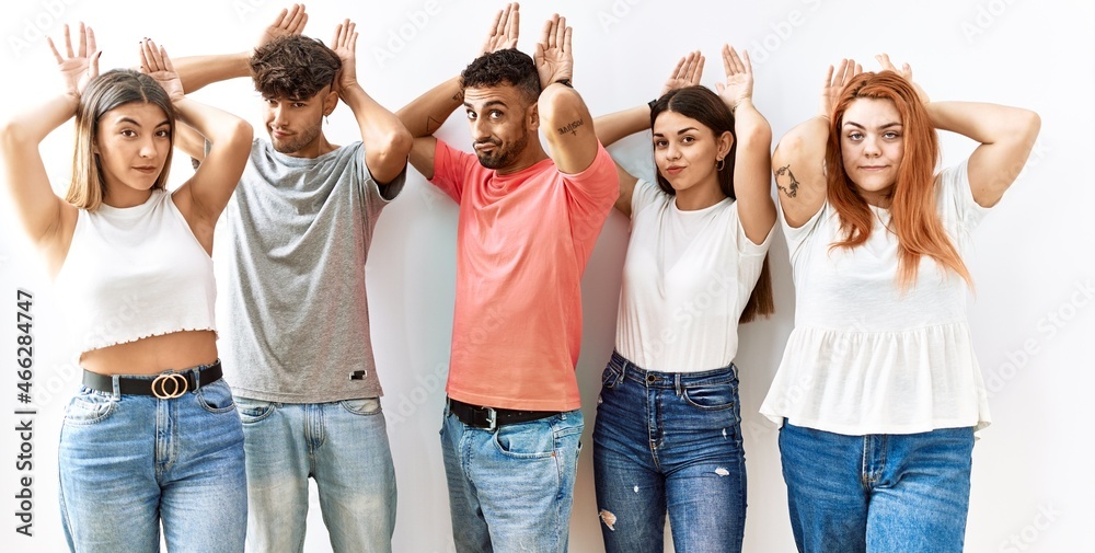 Obraz premium Group of young friends standing together over isolated background doing bunny ears gesture with hands palms looking cynical and skeptical. easter rabbit concept.