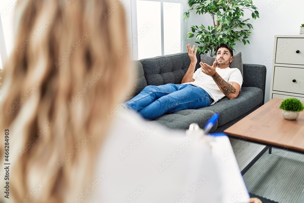 Handsome hispanic man lying on the sofa speaking at psychology consultation Handsome hispanic man lying on the sofa speaking at psychology consultation