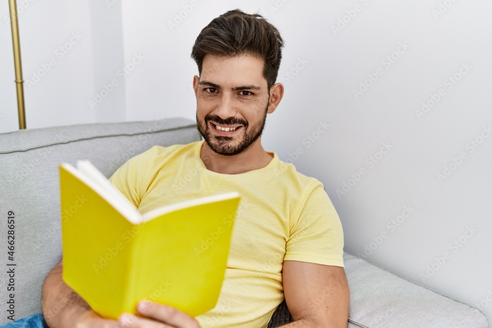 Young hispanic man reding book lying on the sofa at home. Young hispanic man reding book lying on the sofa at home.