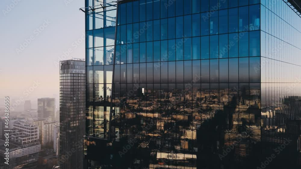 Modern business districtcity glass skyscrapers drone zoom in close to the buildings. Skyscraper in the big city top view during the sunrise when first sun rays are going through the glass windows.