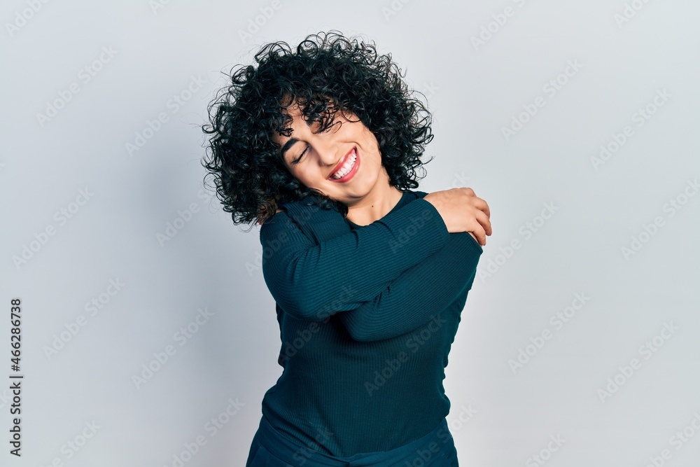 Young middle east woman wearing casual clothes hugging oneself happy and positive, smiling confident. self love and self care