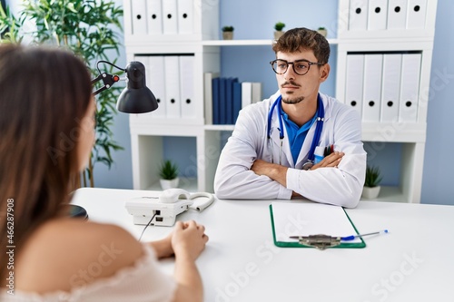 Fototapeta Naklejka Na Ścianę i Meble -  Young doctor with client at medical clinic relaxed with serious expression on face. simple and natural looking at the camera.