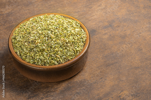 Dried oregano spice on a wooden background. Heap of oregano in a clay bowl. Copyspace
