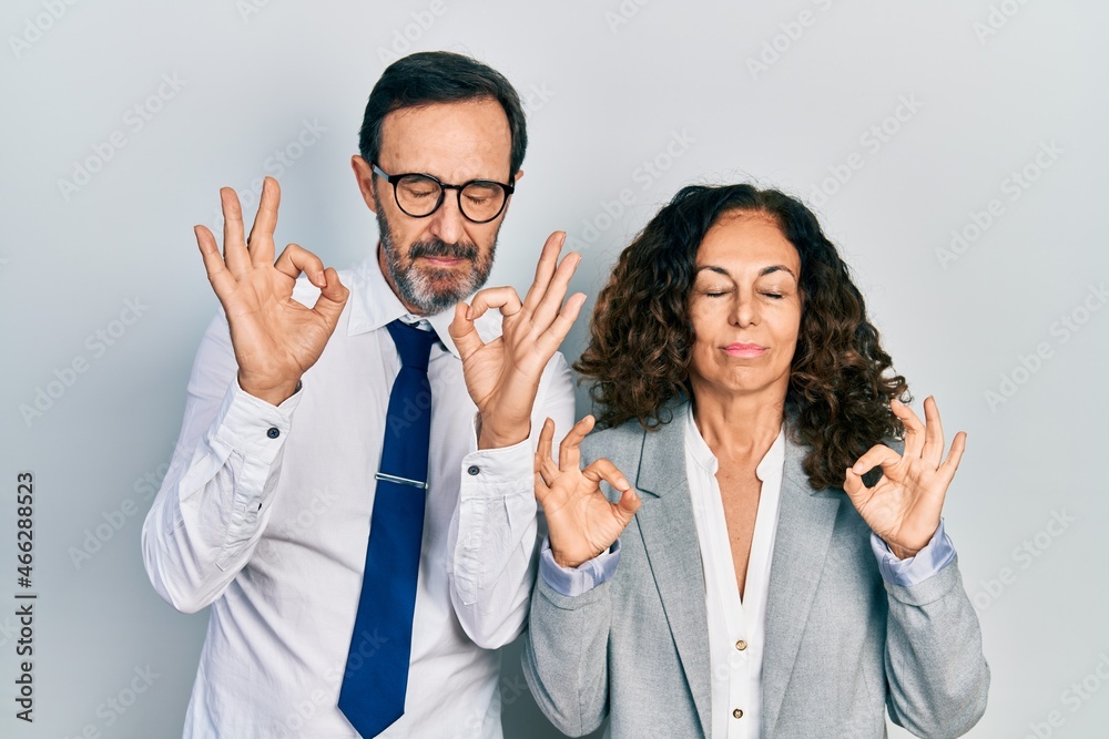 Middle age couple of hispanic woman and man wearing business office uniform relax and smiling with eyes closed doing meditation gesture with fingers. yoga concept. Middle age couple of hispanic woman and man wearing business office uniform relax and smiling with eyes closed doing meditation gesture with fingers. yoga concept.
