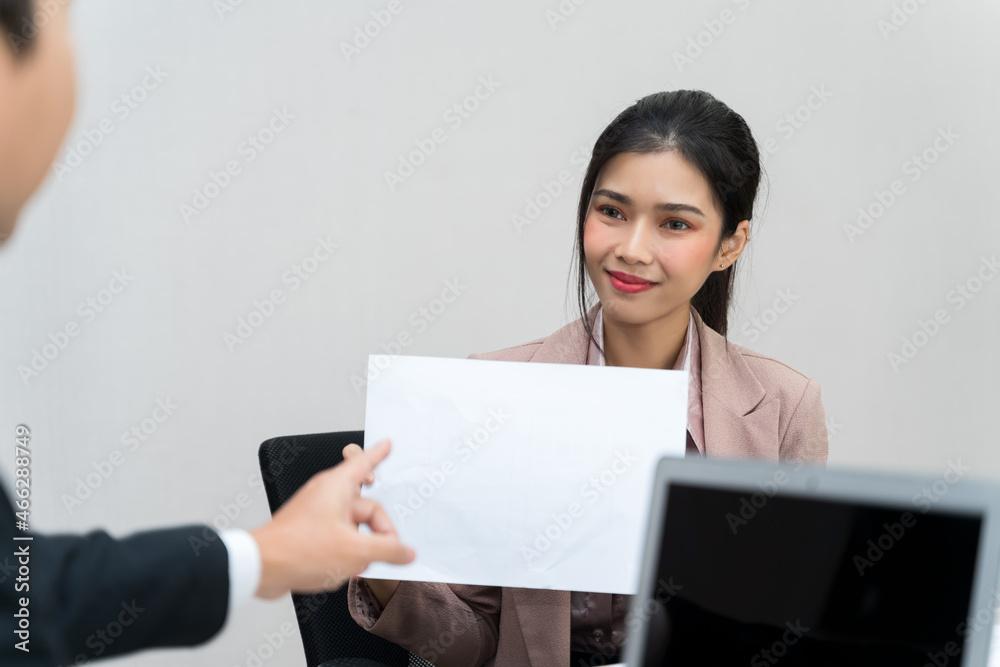 Asian Female staff are presenting and holding blank paper in their hands. The manager is pointing to the documents she is presenting. Copy space on blank paper for your text or advertising media. Asian Female staff are presenting and holding blank paper in their hands. The manager is pointing to the documents she is presenting. Copy space on blank paper for your text or advertising media.