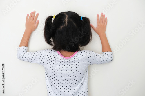 Back view of kid facing wall and put her hands up photo