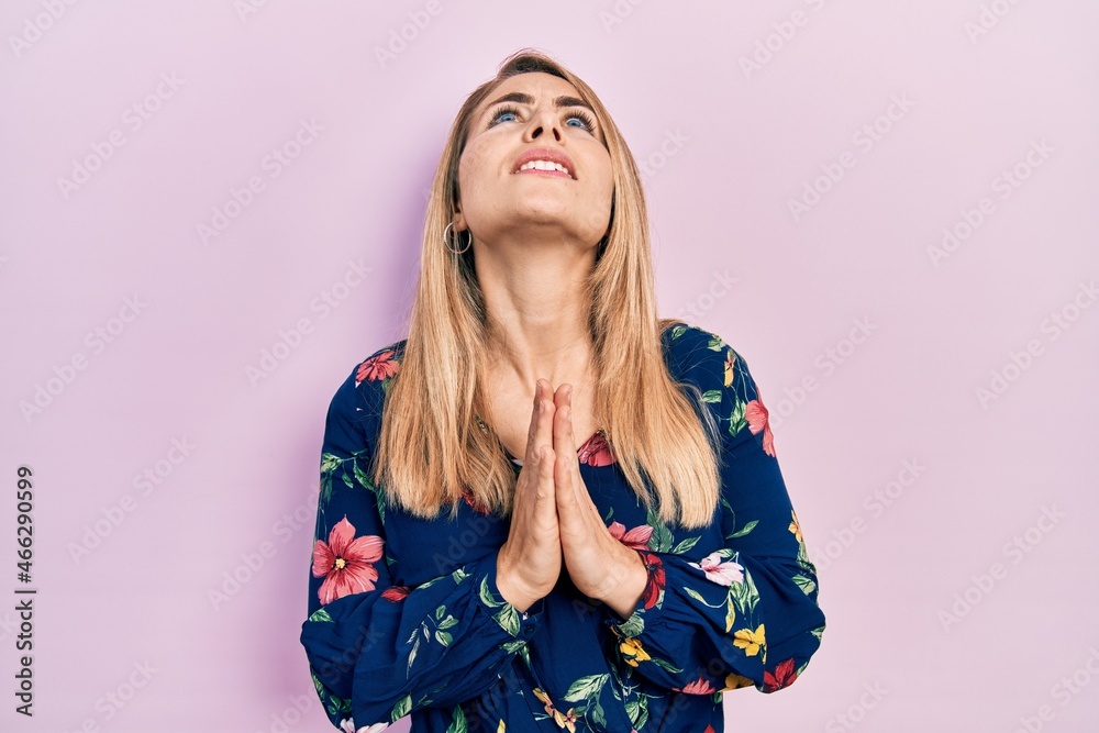 Young caucasian woman wearing casual clothes begging and praying with hands together with hope expression on face very emotional and worried. begging. Young caucasian woman wearing casual clothes begging and praying with hands together with hope expression on face very emotional and worried. begging.