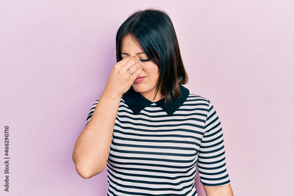 Young hispanic woman wearing casual clothes tired rubbing nose and eyes feeling fatigue and headache. stress and frustration concept. Young hispanic woman wearing casual clothes tired rubbing nose and eyes feeling fatigue and headache. stress and frustration concept.