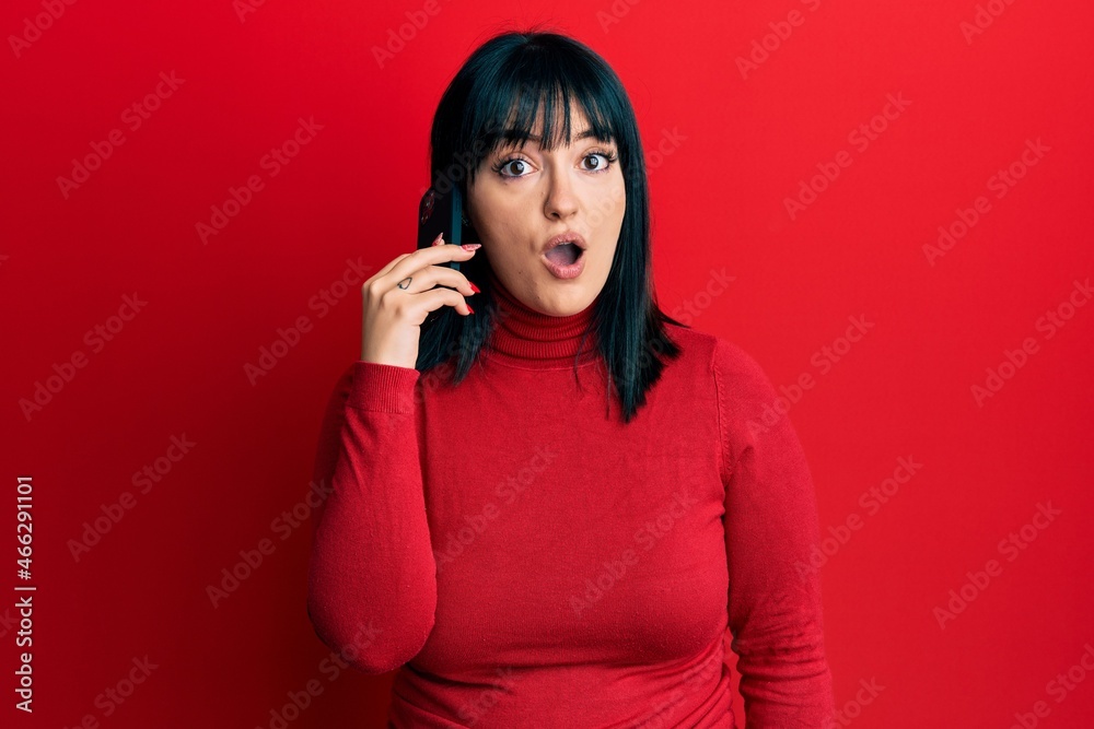 Young hispanic woman having conversation talking on the smartphone scared and amazed with open mouth for surprise, disbelief face Young hispanic woman having conversation talking on the smartphone scared and amazed with open mouth for surprise, disbelief face