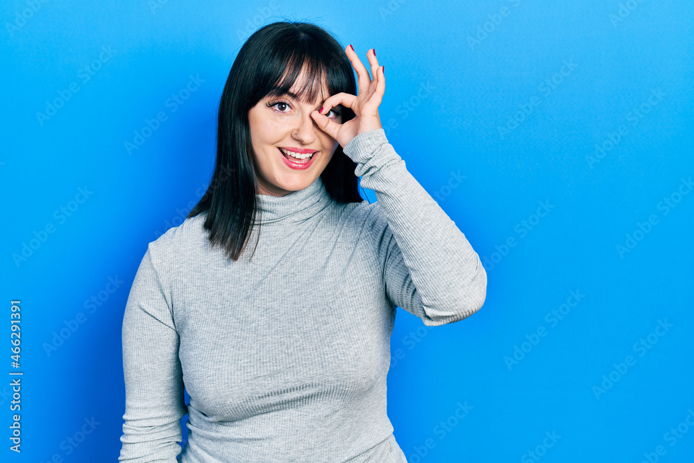 Young hispanic woman wearing casual clothes doing ok gesture with hand smiling, eye looking through fingers with happy face. Young hispanic woman wearing casual clothes doing ok gesture with hand smiling, eye looking through fingers with happy face.