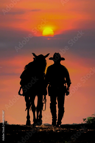 Fotobehang The silhouette of the cowboy and the setting sunset