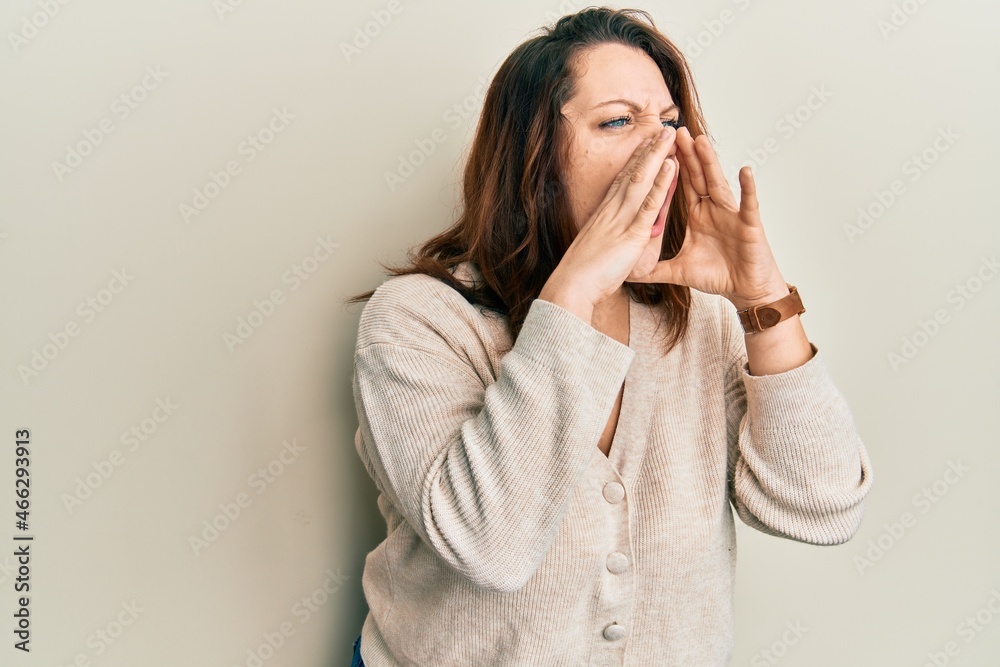 Young caucasian woman wearing casual clothes shouting angry out loud with hands over mouth Young caucasian woman wearing casual clothes shouting angry out loud with hands over mouth