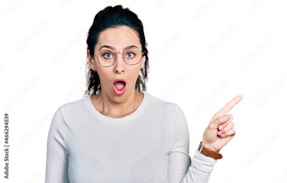 Young hispanic woman pointing with fingers to the side afraid and shocked with surprise and amazed expression, fear and excited face.