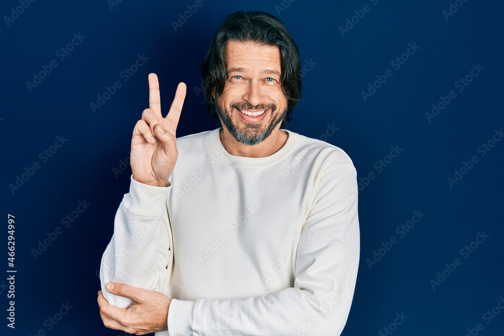 Middle age caucasian man wearing casual clothes smiling with happy face winking at the camera doing victory sign. number two. Middle age caucasian man wearing casual clothes smiling with happy face winking at the camera doing victory sign. number two.
