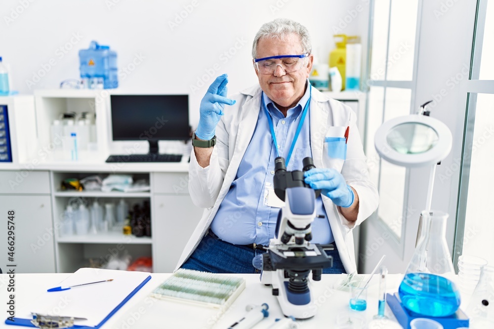 Senior caucasian man working at scientist laboratory gesturing finger crossed smiling with hope and eyes closed. luck and superstitious concept. Senior caucasian man working at scientist laboratory gesturing finger crossed smiling with hope and eyes closed. luck and superstitious concept.