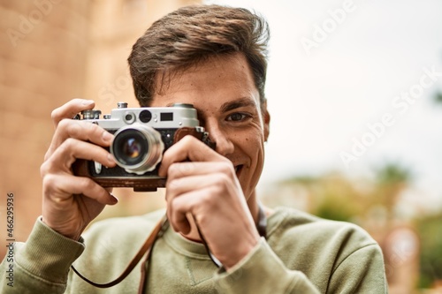 Young hispanic tourist man smiling happy using vintage camera at the city. © Krakenimages.com