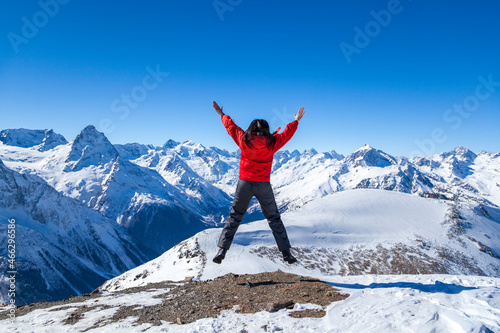Freedom concept, girl looks at snowy mountains on blue sky background © evgenii