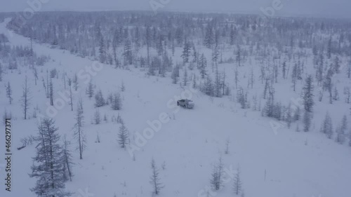 The SUV is driving alone through deep snow in the boundless tundra, the footages are removed from the quadcopter
 photo