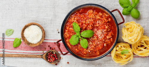 Traditional italian Bolognese sauce in saucepot an old dark wooden background. Top view, copy space